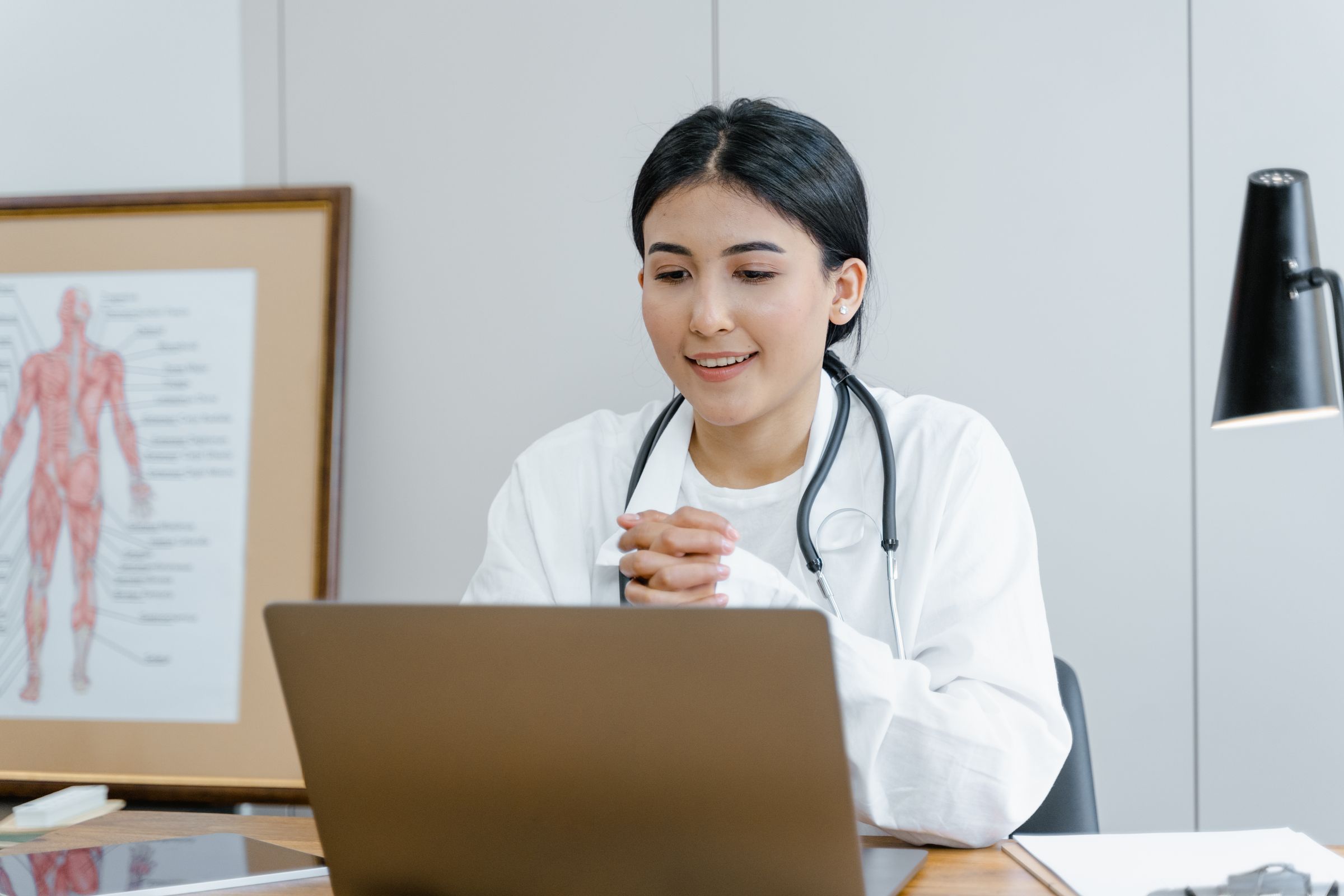 Smiling doctor with a stethoscope at her desk.
