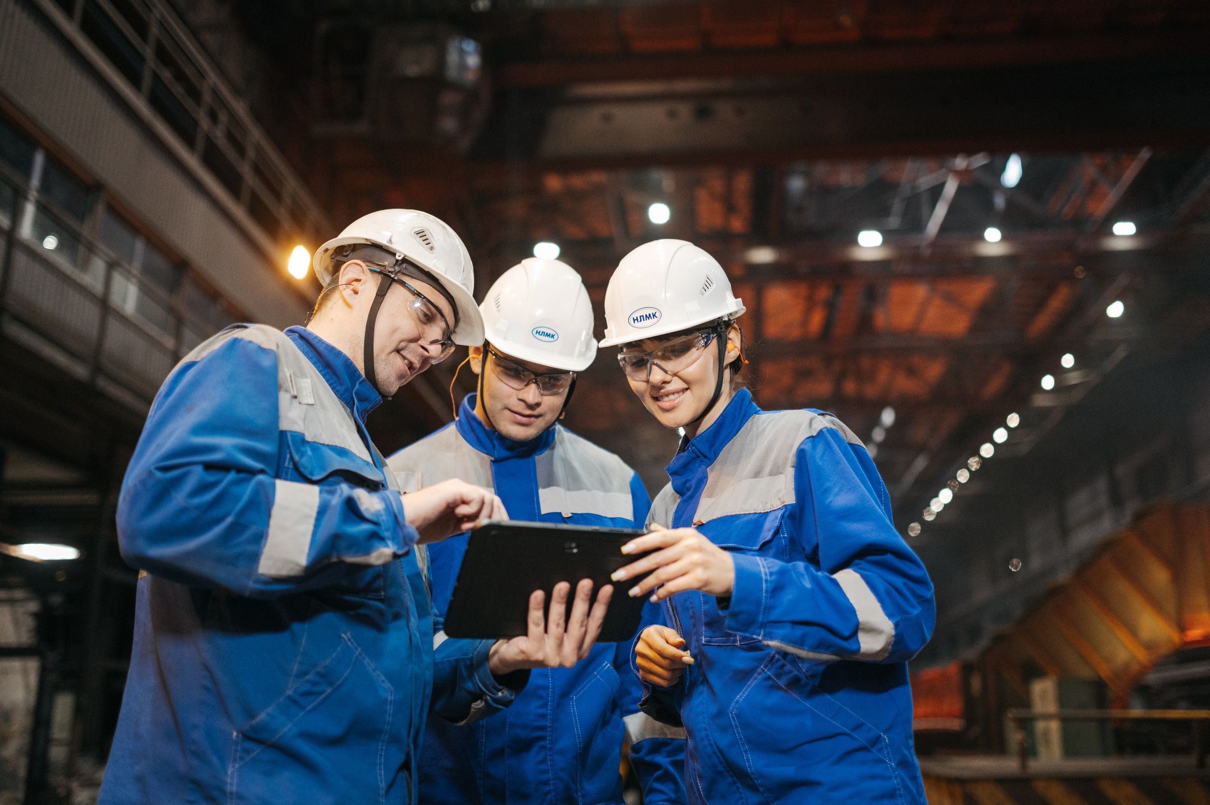 Engineers in hard hats reviewing a plan on a tablet.